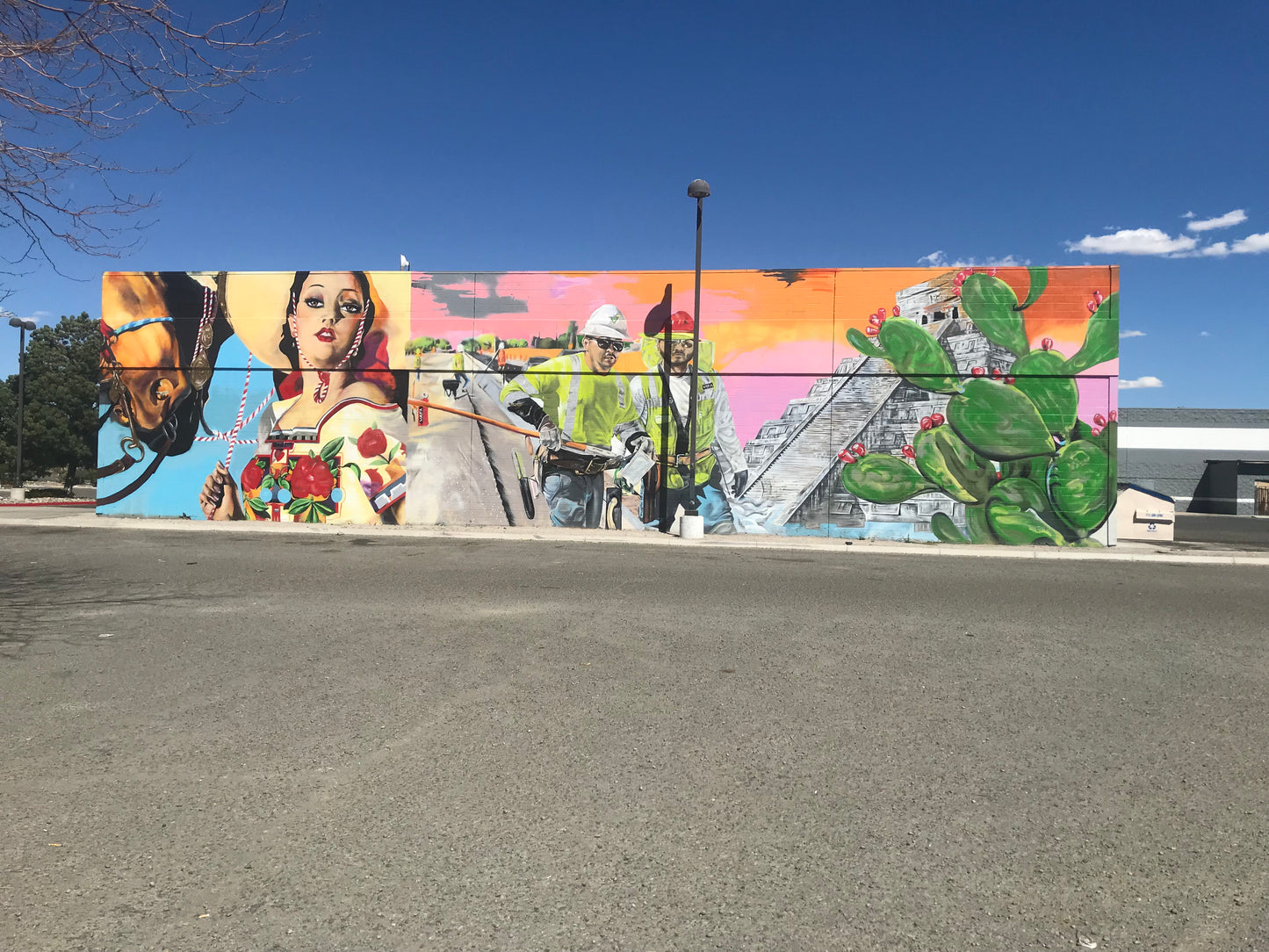 Colorful mural on a wall with various elements including a horse, people, and cacti.