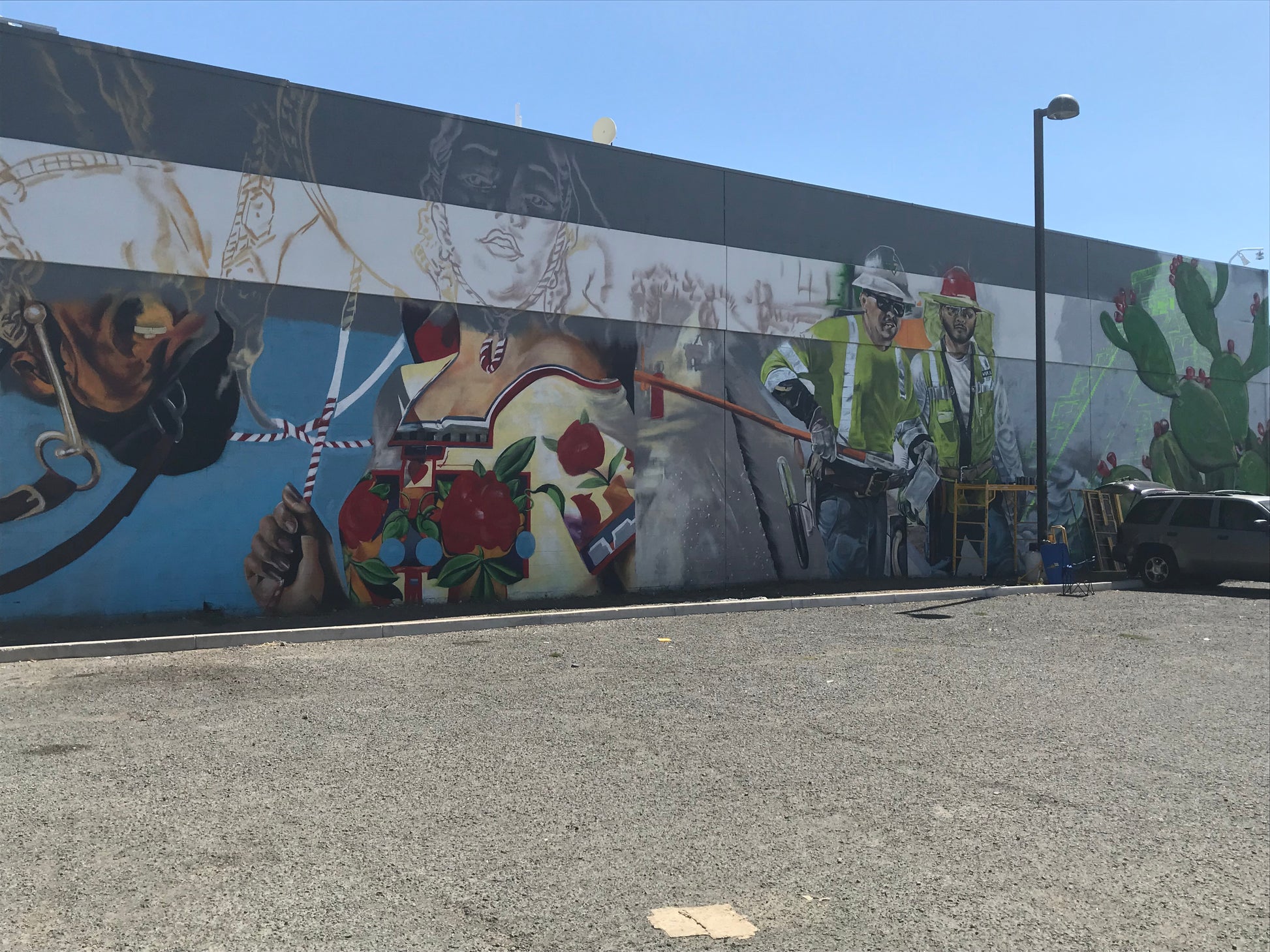 Mural on a wall with various elements including people, animals, and objects.