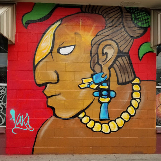 Mural of a stylized face with colorful accessories on a red wall.