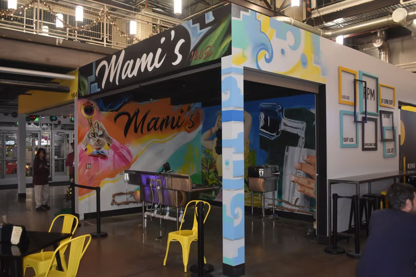 Colorful outdoor food stand with 'Mami's' branding in an indoor setting.