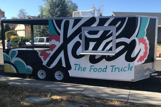 Food truck with colorful design and 'The Food Truck' text on a street.