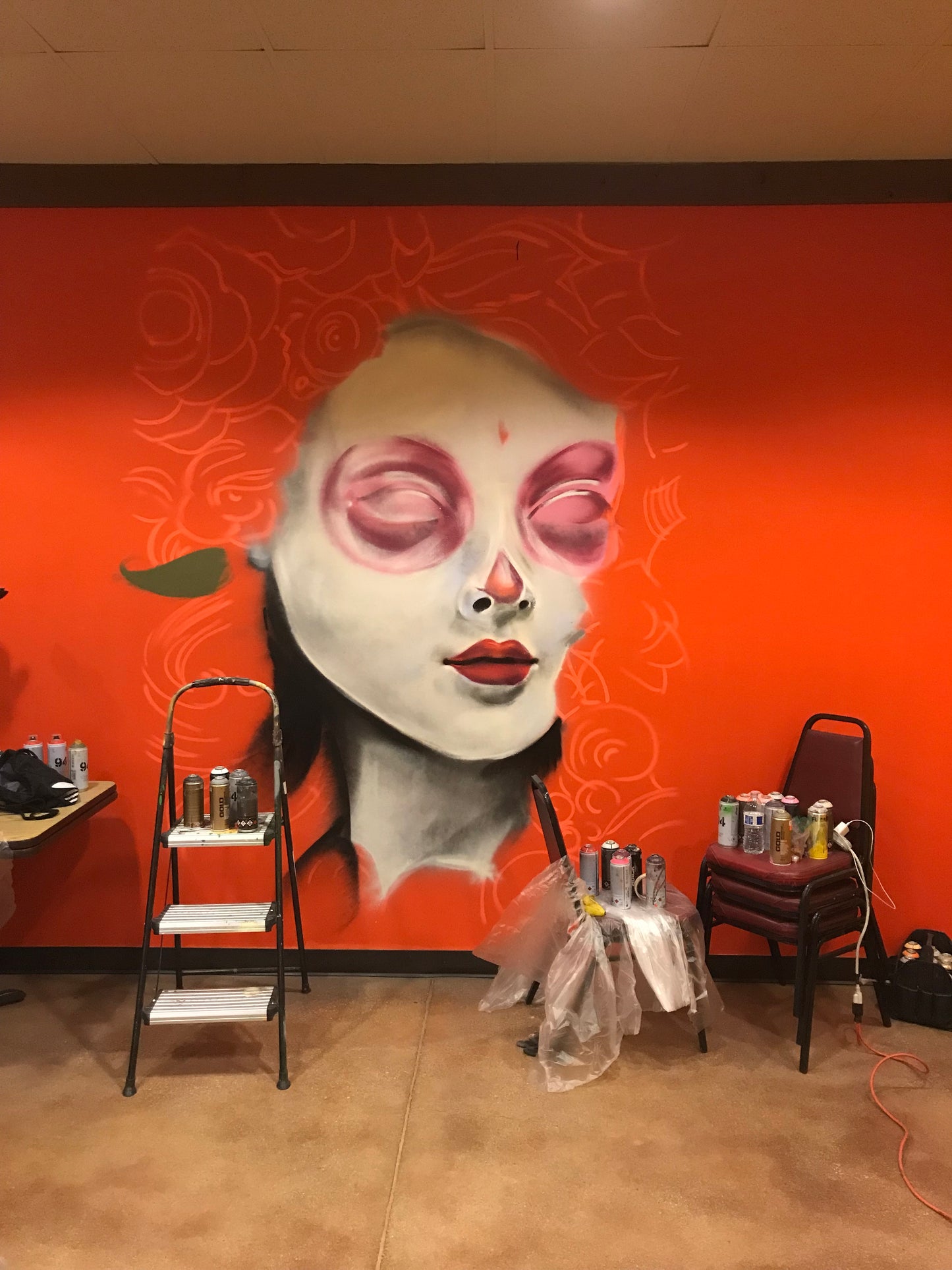 Halloween mask on a stand against an orange wall with decorative patterns
