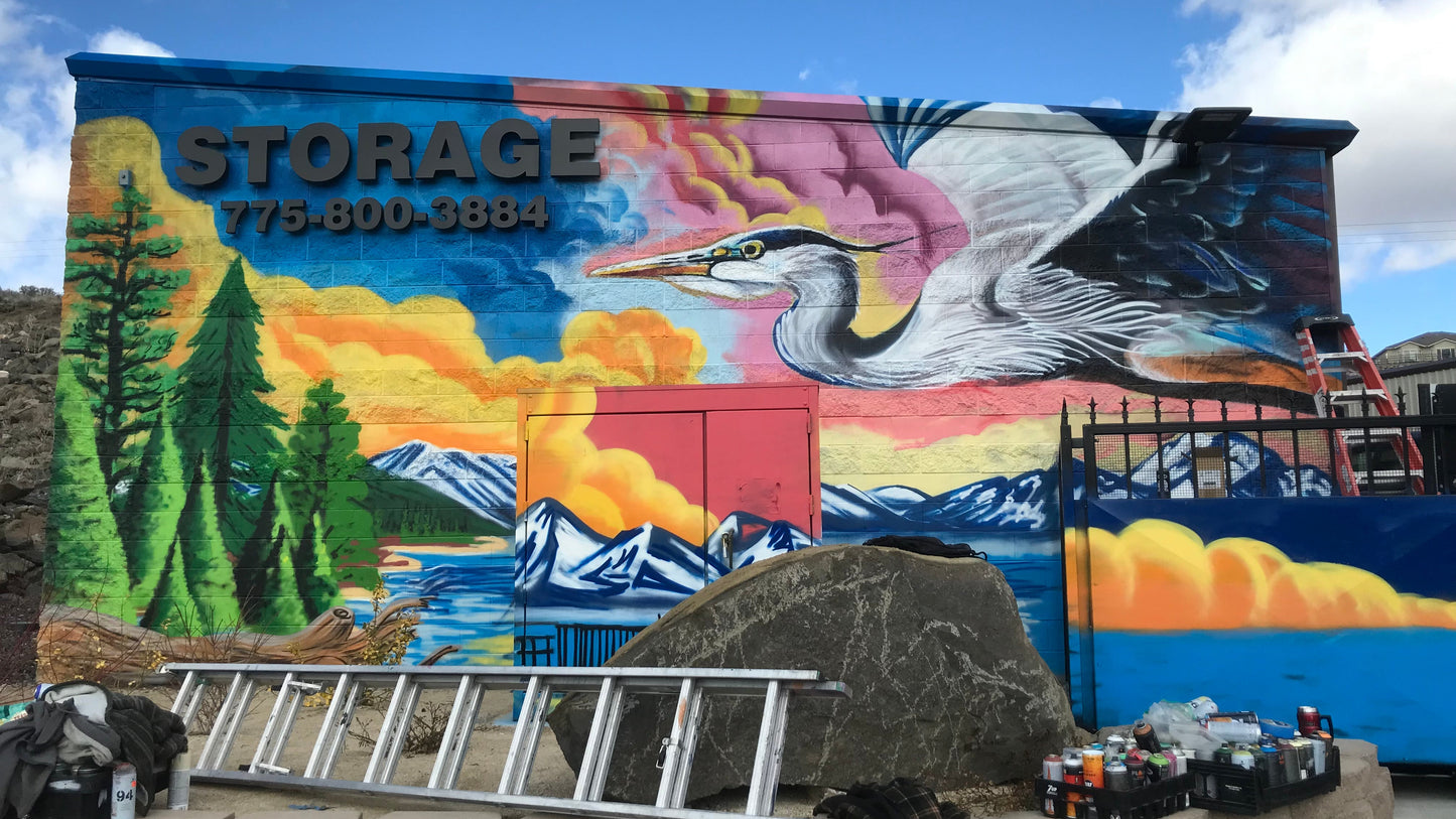 Mural on a storage building with a large bird, trees, and mountains.
