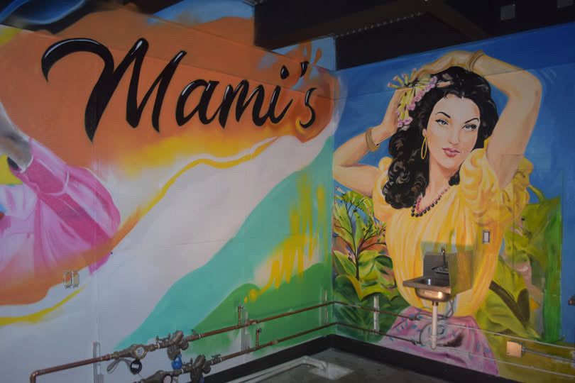 Colorful mural with 'Mami's' branding and a stylized woman in a yellow dress.