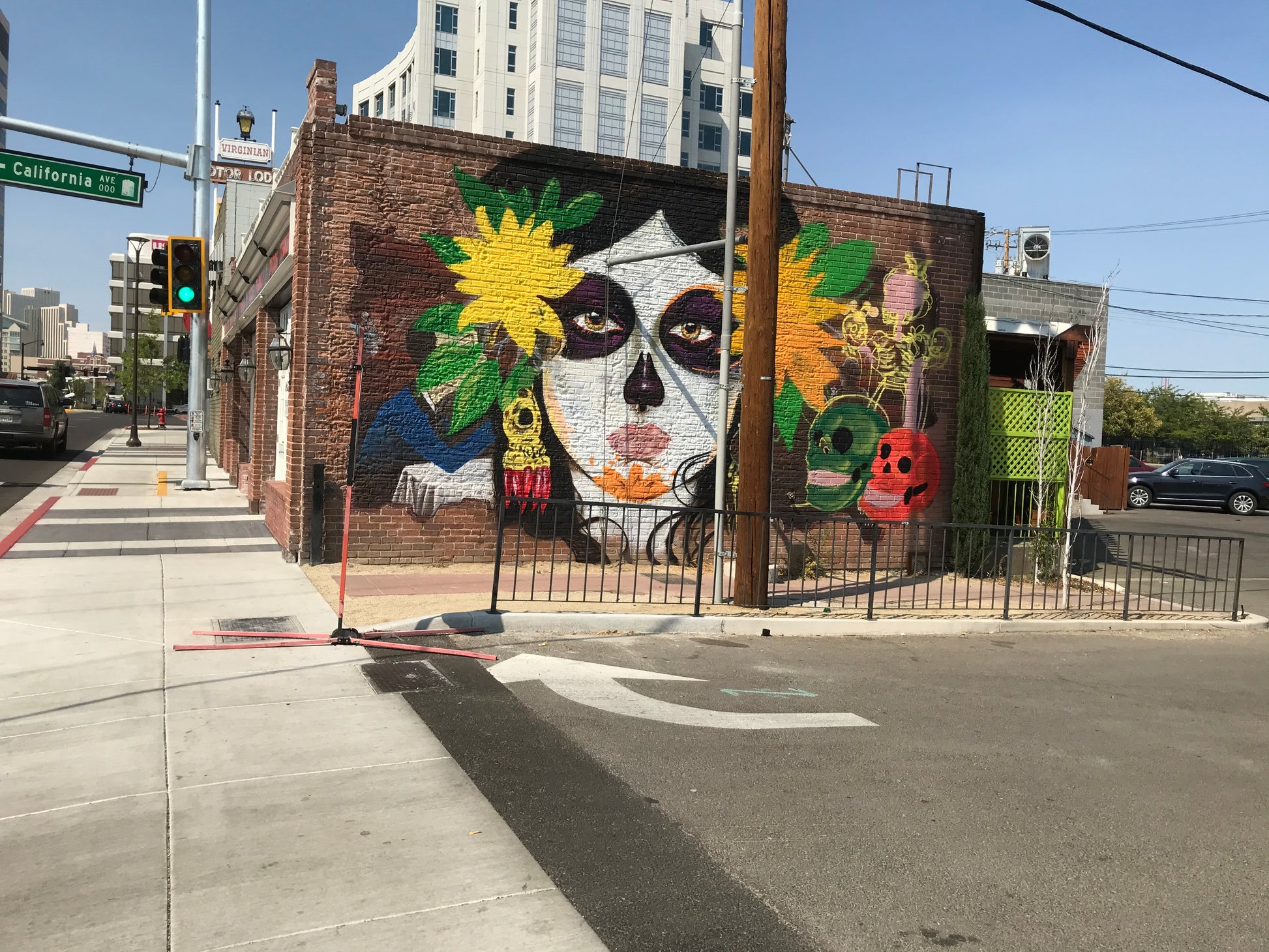 Colorful mural on a brick wall in an urban setting with traffic lights and buildings in the background.