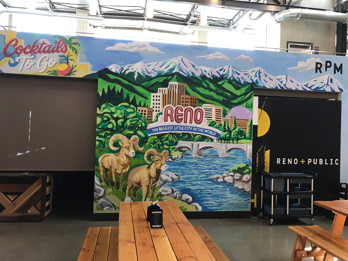 Mural of Reno with mountains and a cityscape, featuring Rams and a bridge.