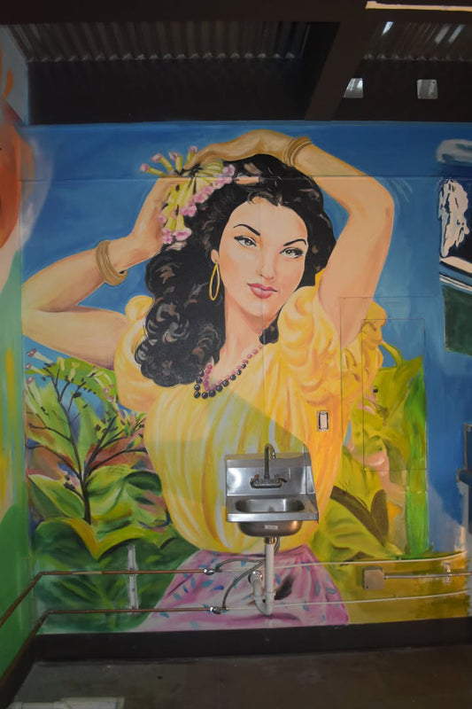 Mural of a woman with flowers in her hair in a colorful setting.
