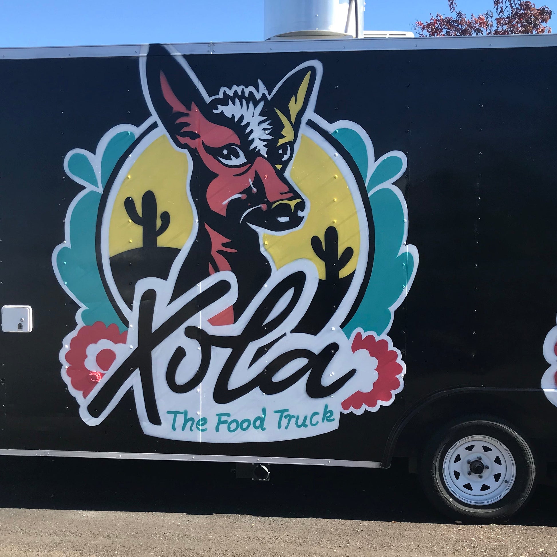 Xola The Food Truck logo on a black food truck with a colorful donkey illustration.